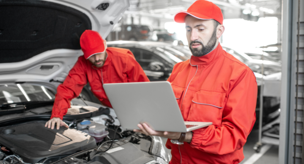 Deux mécaniciens automobiles en uniforme rouge effectuant des diagnostics de moteur avec la valise de diagnostic Logicat launch Maroc dans le service automobile.